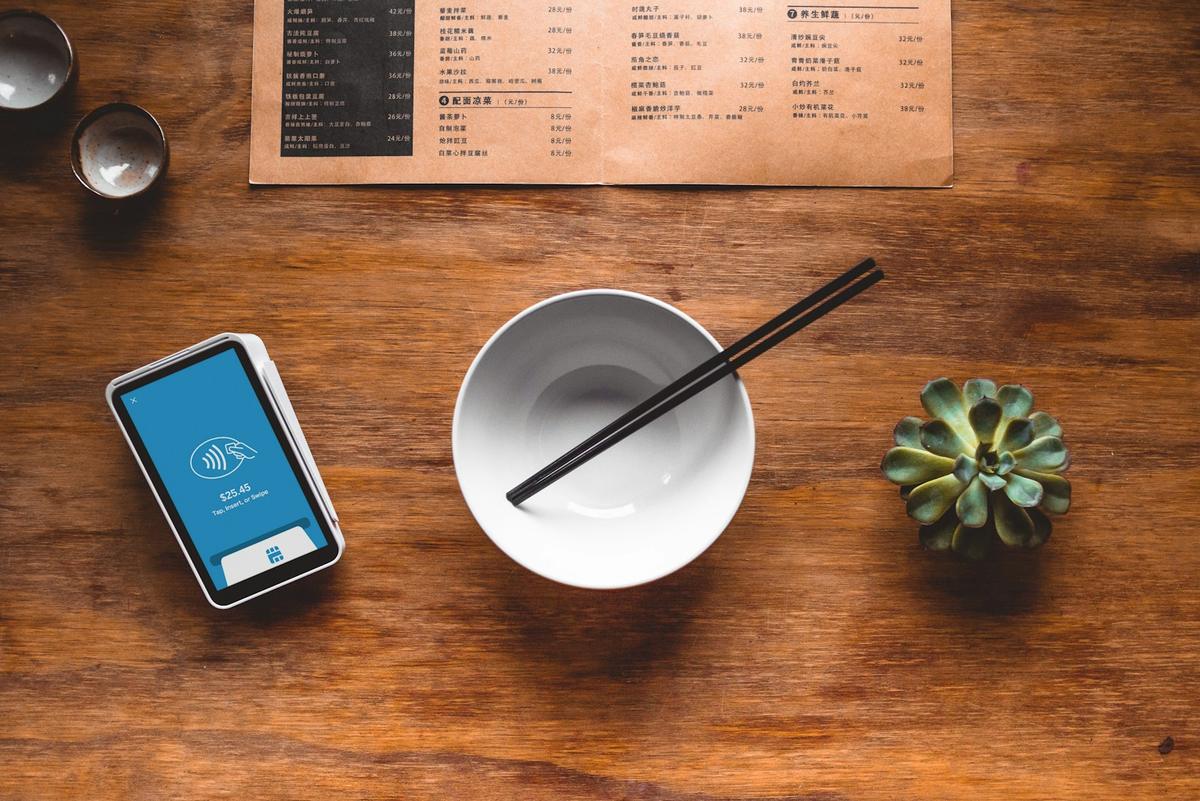 A phone next to a bowl and chopsticks